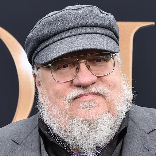 A light-skinned man with large round glasses, a white beard and mustache, and a gray hat