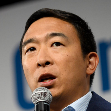 An East Asian man with short black hair, speaking into a microphone